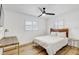 Minimalist bedroom featuring wood floors, ceiling fan, large windows, and a comfortable bed at 9100 2Nd N St, St Petersburg, FL 33702