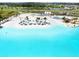 Aerial view of lagoon with sandy beach featuring lounge chairs, water volleyball and a tiki bar at 9617 Branching Ship Trce, Wesley Chapel, FL 33545