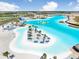 Aerial shot of an outdoor resort lagoon, showcasing its large slide, inflatable course, beach and tiki bar at 9617 Branching Ship Trce, Wesley Chapel, FL 33545