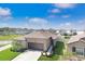 Aerial view shows a tan single-story home in a well-planned neighborhood near a body of water under a sunny sky at 9617 Branching Ship Trce, Wesley Chapel, FL 33545
