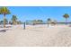 Bright beach featuring a volleyball court, white sand, palm trees, and tiki huts in a resort community at 9617 Branching Ship Trce, Wesley Chapel, FL 33545
