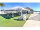A pristine white event tent with tables and chairs, set on artificial turf next to a tiki bar and pool at 9617 Branching Ship Trce, Wesley Chapel, FL 33545