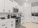Modern kitchen boasts stainless steel appliances, white cabinetry, and stone backsplash at 9617 Branching Ship Trce, Wesley Chapel, FL 33545