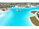 Aerial view of a resort-style lagoon, highlighting the inflatable obstacle course and water slide at 9617 Branching Ship Trce, Wesley Chapel, FL 33545
