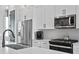 Modern kitchen featuring stainless steel appliances, white cabinets, stylish backsplash, and sleek black fixtures at 98 29Th S St, St Petersburg, FL 33712