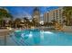 Resort-style swimming pool with lounge chairs and umbrellas surrounded by palm trees at 100 1St N Ave # 1005, St Petersburg, FL 33701