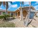 Charming home exterior featuring arched doorway, tropical landscaping, a patterned brick drive, and a blue garage at 1012 Spindle Palm Way, Apollo Beach, FL 33572