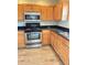 A kitchen featuring wood cabinets, black countertops, and stainless steel appliances at 10316 Carrollwood Ct # 57, Tampa, FL 33618