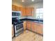 A kitchen featuring wood cabinets, black countertops, and stainless steel appliances at 10316 Carrollwood Ct # 57, Tampa, FL 33618