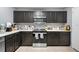 Well-lit kitchen featuring dark cabinetry, modern stainless steel appliances, and ample counter space at 10849 Kensington Park Ave, Riverview, FL 33578
