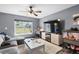 Cozy living room with a large window, ceiling fan, hardwood floors, and a comfortable gray sofa at 10849 Kensington Park Ave, Riverview, FL 33578