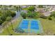 Aerial view of well maintained blue and green tennis courts next to a pond and surrounded by mature trees at 11728 Carissa Ln # 0, New Port Richey, FL 34654