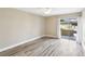 Bright bedroom with wood-look floors, neutral paint, and a sliding glass door to the patio at 1203 16Th Se Cir, Largo, FL 33771