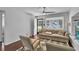 Bright living room featuring hardwood floors, a ceiling fan, and a neutral-toned sofa with stylish chairs at 129 Nw Lincoln N Cir, St Petersburg, FL 33702
