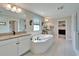 Bright bathroom featuring a large tub, double vanity with granite counter tops, and walk-in closet at 13042 Pennybrook Dr, Riverview, FL 33579