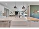 Modern kitchen with farmhouse sink, quartz countertops, and an open layout to the living area at 13042 Pennybrook Dr, Riverview, FL 33579