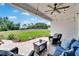 A cozy covered patio features string lights, ceiling fan, and cushioned seating overlooking the manicured lawn at 13042 Pennybrook Dr, Riverview, FL 33579