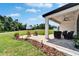 A covered patio includes lounge seating, string lights and a ceiling fan, with a picturesque backyard view at 13042 Pennybrook Dr, Riverview, FL 33579