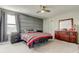 Comfortable bedroom with gray accent wall, ceiling fan, carpet, and window with curtains at 13923 Arbor Pines Dr, Riverview, FL 33579
