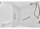 Accessible walk-in shower with grab bars and built-in shelving in an all-white bathroom at 171 Medallion Blvd # F, Madeira Beach, FL 33708