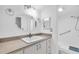 Bathroom with a single sink vanity, octagonal mirror, and step-in shower with grab bars at 171 Medallion Blvd # F, Madeira Beach, FL 33708