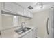 Bright kitchen featuring white cabinetry, a stainless steel refrigerator, and double bowl sink at 171 Medallion Blvd # F, Madeira Beach, FL 33708