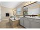 Bright bathroom with a soaking tub, dual sinks, white cabinets, and a large mirror at 19810 Prince Benjamin Dr, Lutz, FL 33549