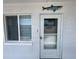 A white front door with a screen and address number, located next to a window and a shark decoration at 2077 Canal Dr # L35, Bradenton, FL 34207