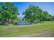 Expansive green backyard with mature trees and a view of the lake at 2344 Pleasant Hill Ln, Holiday, FL 34691