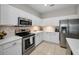 Well-lit kitchen boasts stainless steel appliances, white cabinets, and tiled backsplash at 2344 Pleasant Hill Ln, Holiday, FL 34691