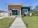 Blue house with a modern wood accent, landscaped yard, and inviting walkway, exuding charm and curb appeal at 2711 W Cordelia St, Tampa, FL 33607