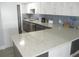 Modern kitchen with stainless steel appliances, white cabinets, gray backsplash, and quartz countertops at 280 126Th Ave # 106, Treasure Island, FL 33706