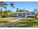 Charming blue single-story home featuring a well-manicured front yard, sidewalk and lush landscaping at 3500 Gussie St, Punta Gorda, FL 33950
