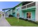 Charming two-story condo building with light-blue siding, green lawn, and a cozy outdoor porch with sliding glass door at 455 Alt 19 # 111, Palm Harbor, FL 34683