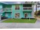 Two-story teal condo building with white trim, green grass, and first and second story outdoor entrances at 455 Alt 19 # 111, Palm Harbor, FL 34683