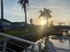 Waterfront view with a dock and the sun setting behind houses and palm trees at 4551 Floramar Ter, New Port Richey, FL 34652