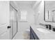 Bright bathroom with shower, blue vanity with granite countertop, and modern black faucet at 5482 Salem Square N Dr, Palm Harbor, FL 34685