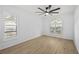 Spacious bedroom featuring wood floors, ceiling fan, and natural light from bright, shuttered windows at 5482 Salem Square N Dr, Palm Harbor, FL 34685