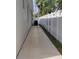 Exterior side yard showcasing a concrete walkway running along the property line with white vinyl fencing at 6690 54Th N Ave, St Petersburg, FL 33709