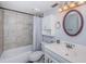 Bathroom with tiled shower and tub combination, white vanity, and decorative mirror at 801 Russell Ln # 255, Brandon, FL 33510