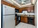 Kitchen featuring a stainless steel refrigerator, granite counters, wooden cabinets, black appliances and tile floors at 801 Russell Ln # 255, Brandon, FL 33510