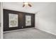 Bedroom featuring two windows, neutral carpeting, ceiling fan, and black accent wall at 10407 Westpark Preserve Blvd, Tampa, FL 33625
