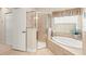 Bathroom featuring frameless glass shower, garden tub with tile surround and window at 11534 Biddeford Pl, New Port Richey, FL 34654