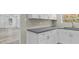 Bright kitchen featuring white cabinets, gray countertops, and stainless steel faucet with a view to the living room at 1209 E 29Th Ave, Tampa, FL 33605