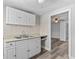 Charming kitchen with white cabinets and double basin sink overlooks an open doorway and wood-look floors at 1209 E 29Th Ave, Tampa, FL 33605