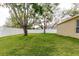 Large backyard with a white fence, mature trees, and green grass extending to the home's exterior at 12506 Safari Ln, Riverview, FL 33579
