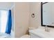 Bright bathroom features a shower with a blue curtain, toilet, and a vanity with a black-framed mirror at 12506 Safari Ln, Riverview, FL 33579