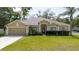 Charming home featuring a red front door, well-manicured landscaping, and an attached garage at 12506 Safari Ln, Riverview, FL 33579