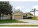 Inviting one-story home with a two-car garage, a well-kept lawn, and a beautiful tree at 12506 Safari Ln, Riverview, FL 33579