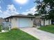 Charming home exterior with a white garage door, decorative iron gate, and well-maintained landscaping at 13930 King Ave, Hudson, FL 34669